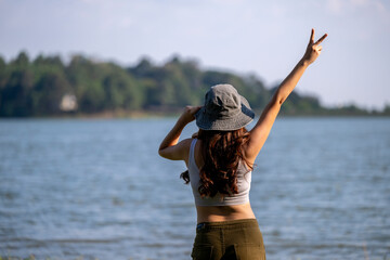 Naklejka premium A woman is standing on the beach with her hands up in the air