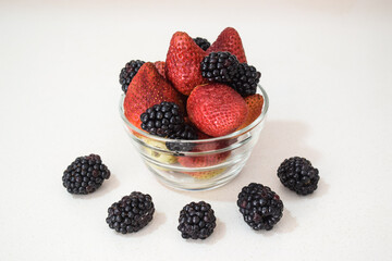 Vibrant blackberries and strawberries in a glass container