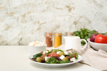 Plate of healthy vegetable salad with feta cheese, grapefruit, olives and basil on white table