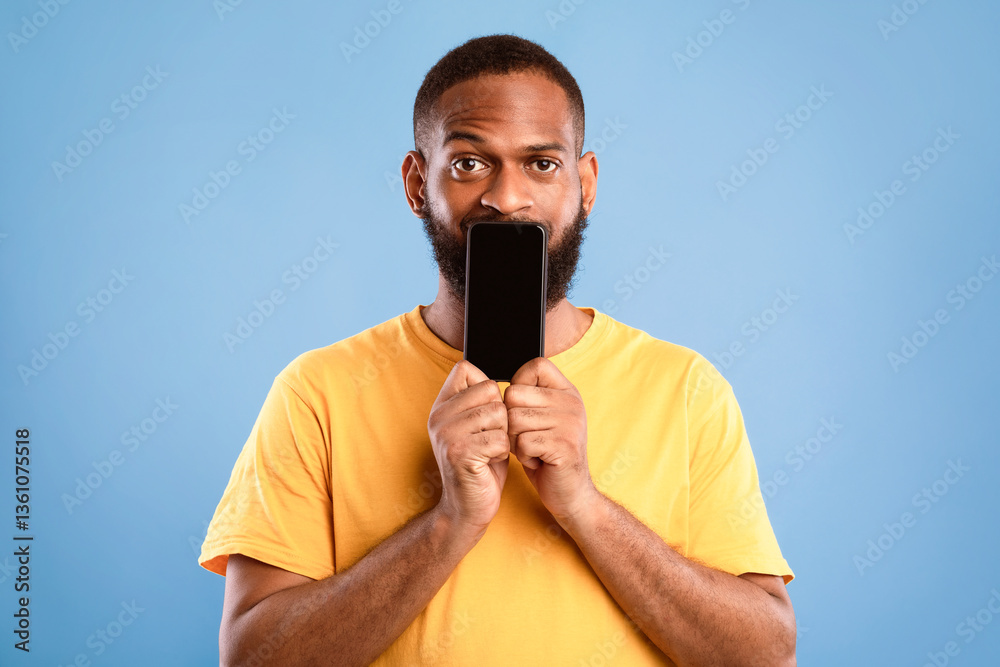 Poster handsome african american man covering is mouth with blank cellphone with mockup for app or website 