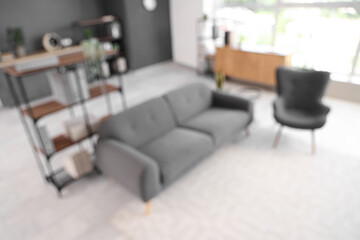 Blurred view of living room with black sofa and armchair