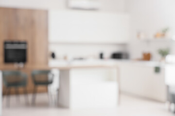 Blurred view of light kitchen with white counters and dining table