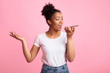Voice Search. Emotional black girl using smart phone voice and talking, holding gadget near mouth