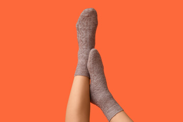 Legs of young woman in grey cotton socks on orange background