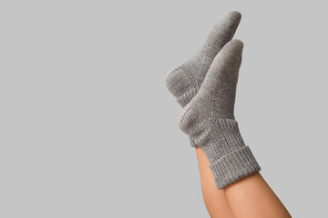 Legs of young woman in warm knitted socks on grey background