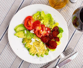 Appetizing fresh lettuce and tomatoes served with chorizo and avocado on platter