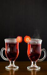 Elegant steaming red drink in glass cups with black background