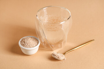 Glass of water with psyllium husk on brown background