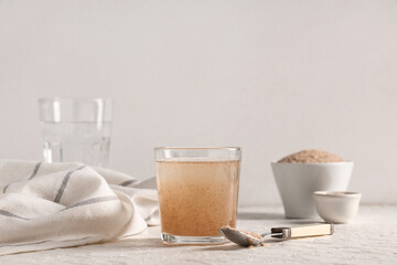Glass of water with psyllium husk on light background