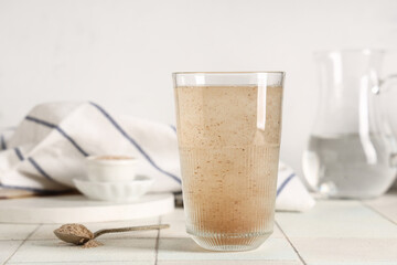 Glass of water with psyllium husk on light background