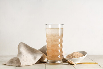 Glass of water with psyllium husk on light background