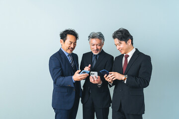 スマホ、スマートフォン、笑顔、ミドルエイジ、シニア、男性、グループ、SNS、DX、動画、ニュース、ゲーム、ビジネス、会社員、サラリーマン、ビジネスマン、ビジネスパーソン、日本人、中高年、中年、チームワーク、セカンドキャリア、社長、経営者、エグゼクティブ、リーダー、管理職、上司、楽しい、面白い、キャンペーン、ポイント、クーポン、見せる、アプリ、マッチング、IT、デジタルトランスフォーメーション、情報