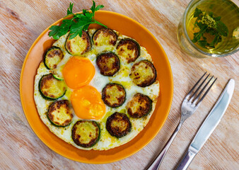 Closeup of cooked eggs with zucchini at plate on table