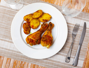 Closeup of homemade baked chicken legs with potatoes on plate