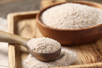 Spoon and bowl with psyllium husk powder on board, closeup