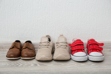 Different children's shoes on floor near white wall