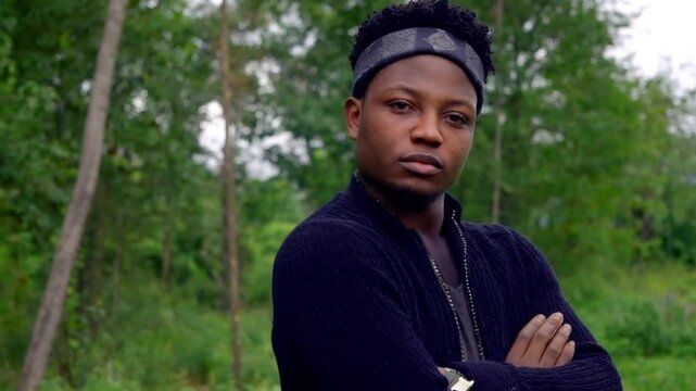 young handsome black man in the forest with crossed arms looking at camera