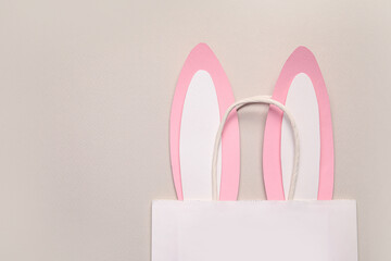 Shopping bag with paper Easter bunny ears on beige background