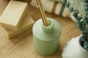 Green bottle with bamboo sticks and soap on a wooden surface