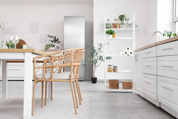 Interior of stylish kitchen with dining table, refrigerator and shelving unit