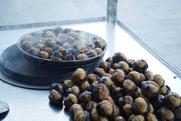 Steam rising from roasted chestnuts at a street vendor