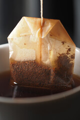 Tea bag steeping in warm cup of black tea by the window
