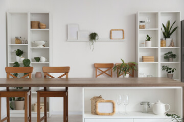 Interior of stylish kitchen with island table, houseplants and shelving units