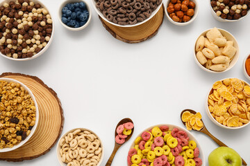 Frame made of bowls with different tasty cereals, dry fruits and nuts on white background