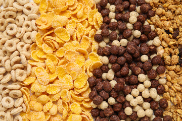 Different tasty scattered cereals as background, closeup