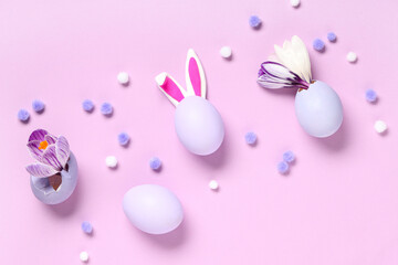 Easter eggs with bunny ears and crocus flowers on pink background