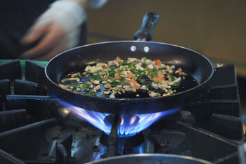 Cooking vegetables in a frying pan over a gas flame