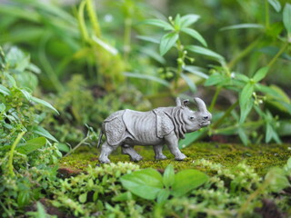 Mini toy of action figure at outdoor with blurred background. Miniature photography concept design. Minifigure of rhinoceros character at nature.