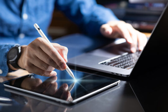 Close-up of a professional working with a laptop and a digital tablet.For creative work such as graphic design, digital illustration, or business tasks in modern workspace.