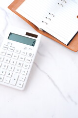 電卓と手帳でデスクワークをしているイメージ
