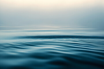 Obraz premium Gentle blue ripples spread across misty water under a pale sky, creating a soothing minimal background ideal for wellness, tech, and presentations.