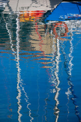Colourfull reflections of the hull and masts of yachts on the water