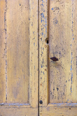 Detail of a wooden door with pealing yellow paint
