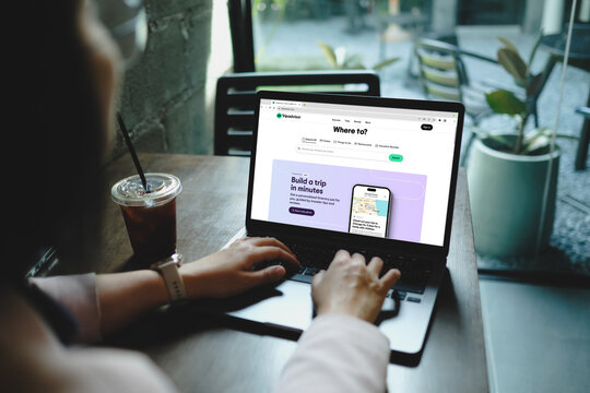 Bangkok, Thailand. March 27, 2025; Person browsing the Tripadvisor website on a laptop while sitting at a wooden table with an iced coffee beside them.