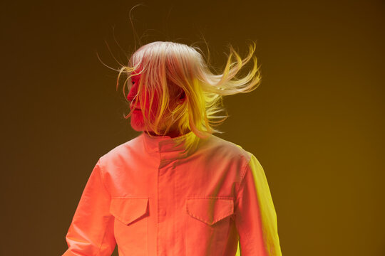 stylish portrait, contemporary fashion, dynamic movement, colored lighting, modern aesthetics, energetic expression, high contrast background, artist in action, vibrant colors, creative photography