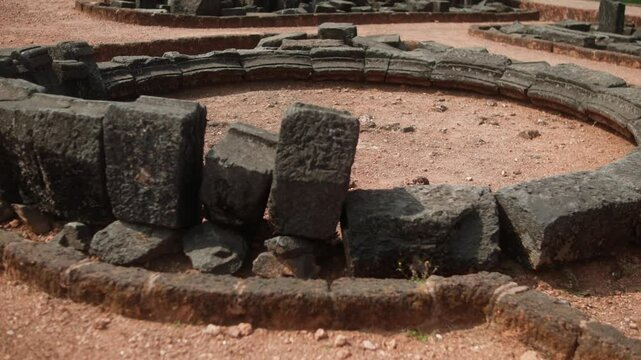 Ancient stone ruins with scattered stones forming circular structures in India