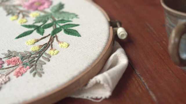 Beautiful embroidery flowers on cotton fabric. Product of needlework on a piece of embroidery. Needlework is decorative sewing and textile arts handicrafts. How to stitch embroider flowers on clothes.