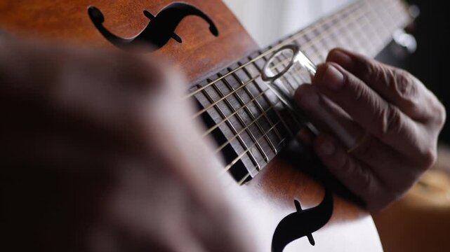 Male musician hand play Vintage Resonator acoustic dobro blues slide guitar.