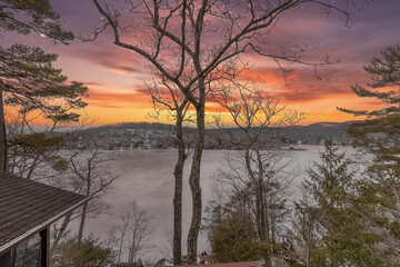 Obraz premium Winter aerial view of Glen Wild Lake in Bloomingdale, New Jersey, surrounded by forested hills and lakeside homes. The frozen landscape highlights seasonal beauty and natural tranquility.