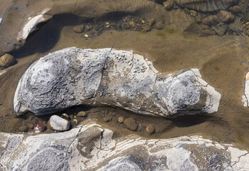 shallow water, the stone bottom of the riverbed on a sunny day, a walk along the stones of the river with an overview of the bottom structure