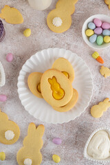 Easter egg-shaped sandwich cookies with orange curd on a white plate on a concrete background....