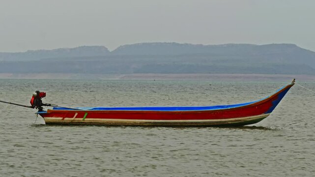 fishing boat waving in krishna river and hill mountain at vizag colony, nagarjuna sagar backwater, azmapur, telangana, andhra pradesh, india. day time, zoom in, 4k.