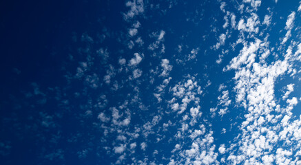 Obraz premium Blue sky with calm clouds background. Bright blue sky background. Cloudscape with white clouds. Calm sky cloudy on a sunny day. Sunlight through the clouds wallpaper. Spring sky with soft clouds.