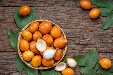 Fresh Achacha fruit or garcinia intermedia in wooden bowl on wooden background, Yellow Madrono Fruit or Lemon drop mangosteen in wooden basket on wooden texture background.