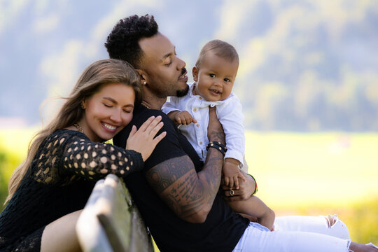 Mixed race family outdoor portrait. Mixed race parents with baby child on nature. Mixed race Portrait of happy african american or hispanic father and caucasian mother with mixed race baby.