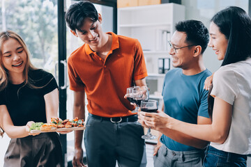Asian office colleagues and friends enjoy a daytime BBQ with pizza and beer, celebrating Halloween and cheering for their favorite soccer team, creating a lively atmosphere filled with joy.